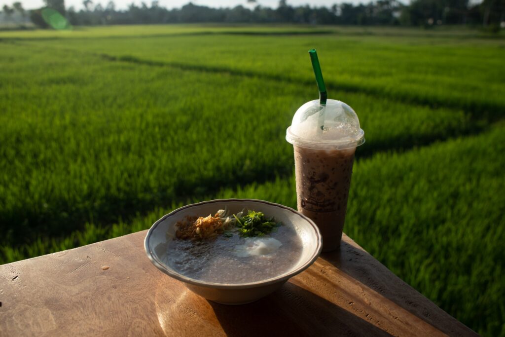 A bowl of rice porridge (Khao Tom) overlooking a rice paddy in Na Muen Sri.