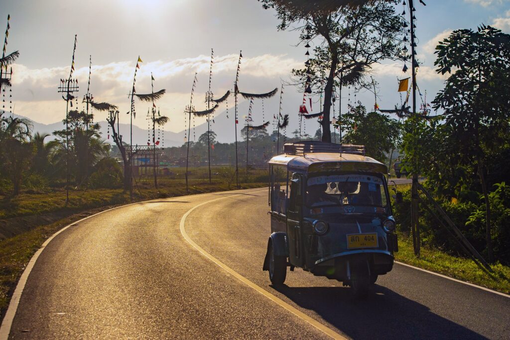 Local tuk-tuk passing through Na Muen Sri wind wheel festival in the early morning.