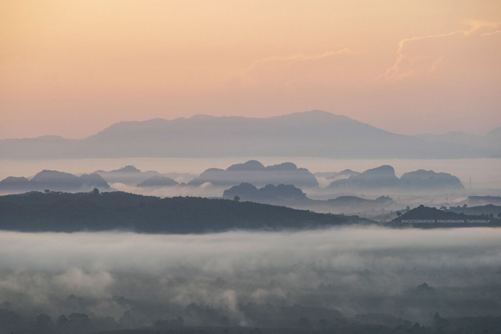Peaks emerge above the clouds at Wang Pa Mek. In the distance, Koh Lanta stands in the Malacca Strait.